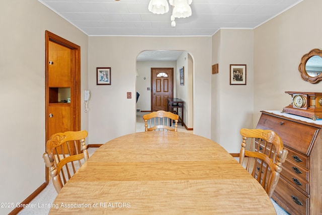 dining room featuring arched walkways, carpet, and baseboards