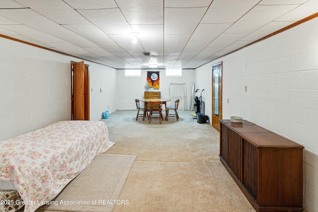 bedroom with concrete block wall and light colored carpet