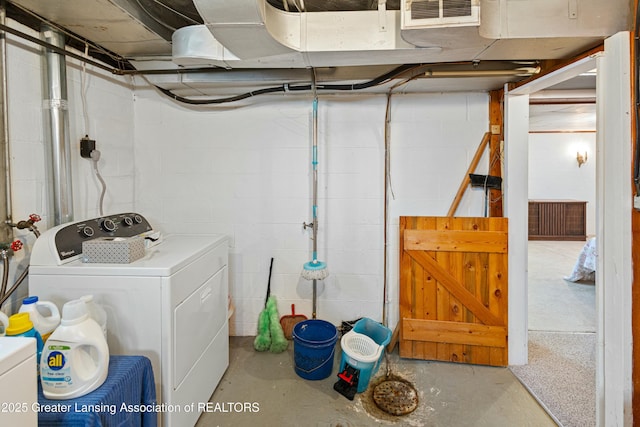 unfinished basement featuring washing machine and clothes dryer, visible vents, and concrete block wall