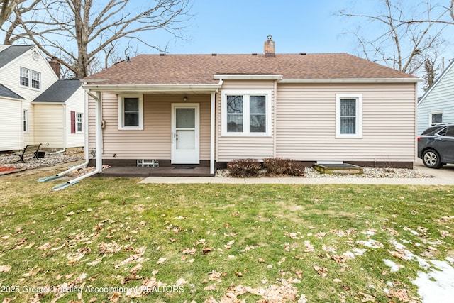 view of front of property featuring a front lawn, a chimney, and a shingled roof