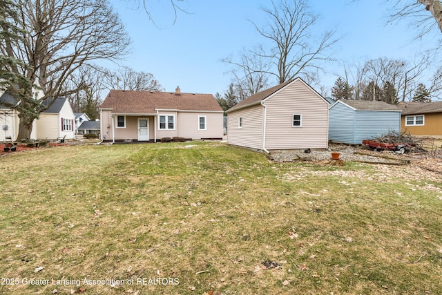 back of property featuring an outbuilding, a yard, and a chimney