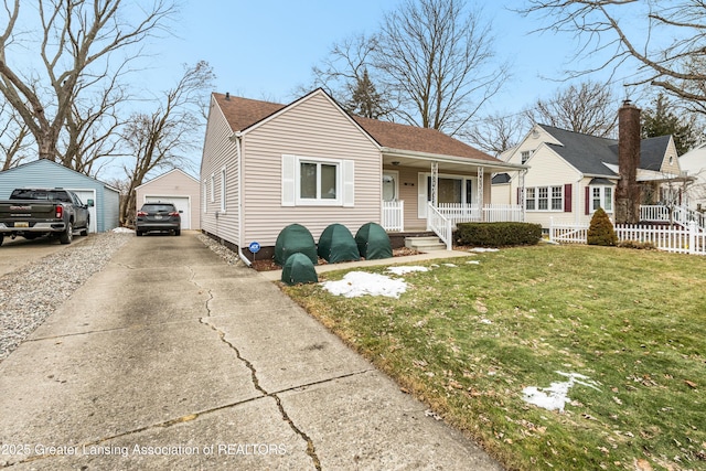 bungalow-style home featuring a shingled roof, a detached garage, a porch, an outdoor structure, and a front lawn