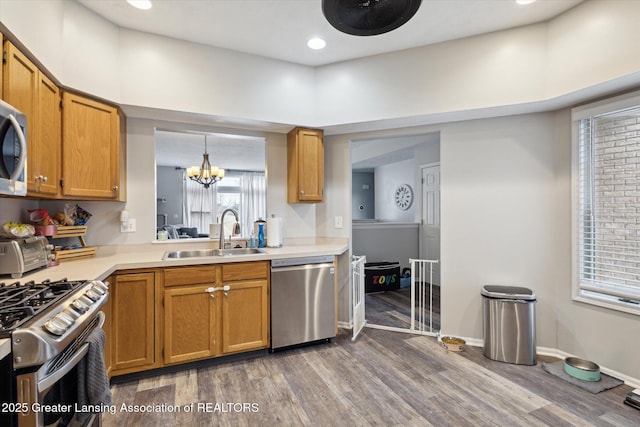 kitchen with stainless steel appliances, wood finished floors, a sink, and light countertops