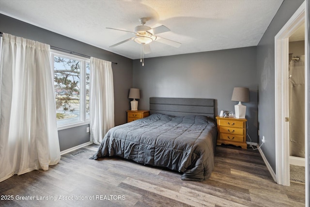 bedroom featuring a textured ceiling, wood finished floors, visible vents, and baseboards