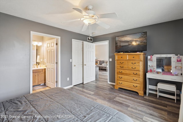 bedroom featuring baseboards, visible vents, ensuite bath, ceiling fan, and wood finished floors