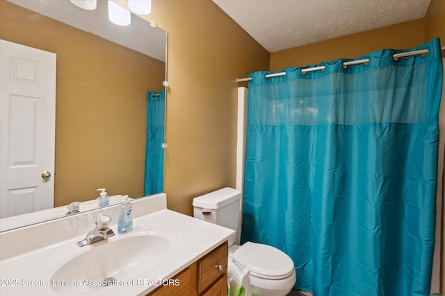 full bathroom featuring toilet, curtained shower, a textured ceiling, and vanity