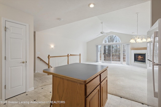 kitchen with lofted ceiling, light colored carpet, ceiling fan with notable chandelier, a center island, and dark countertops