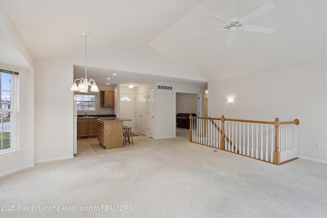 unfurnished living room with high vaulted ceiling, baseboards, visible vents, and light colored carpet