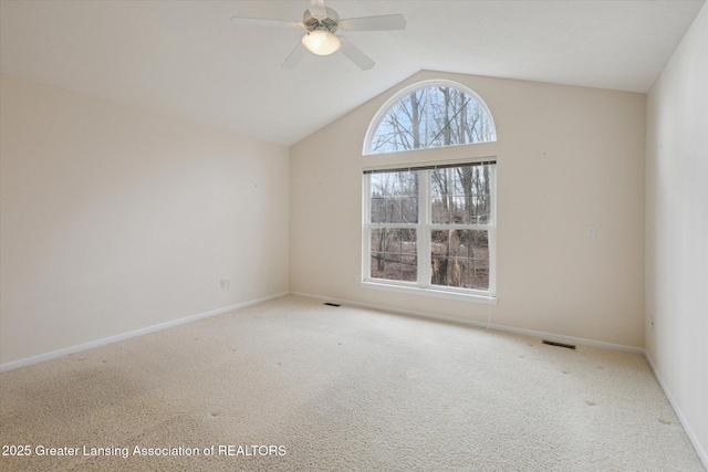 carpeted spare room with lofted ceiling, ceiling fan, visible vents, and baseboards