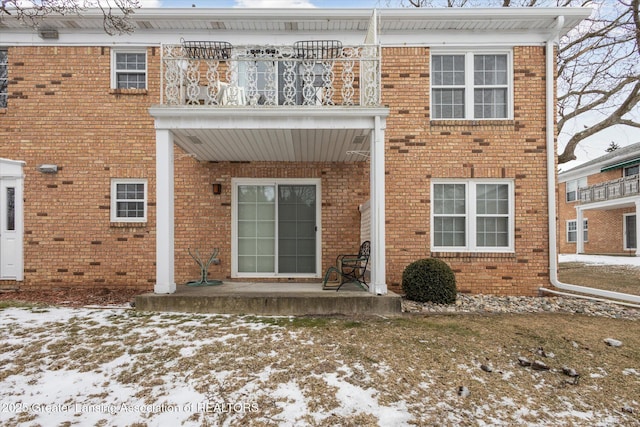 rear view of property with brick siding and a balcony