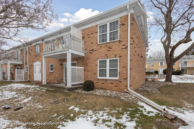 exterior space with a balcony and brick siding