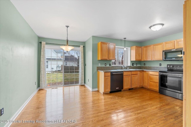 kitchen with hanging light fixtures, appliances with stainless steel finishes, a sink, light wood-type flooring, and baseboards