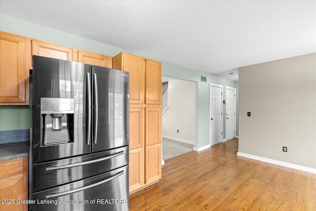 kitchen with stainless steel refrigerator with ice dispenser, visible vents, light wood-style floors, light brown cabinets, and baseboards