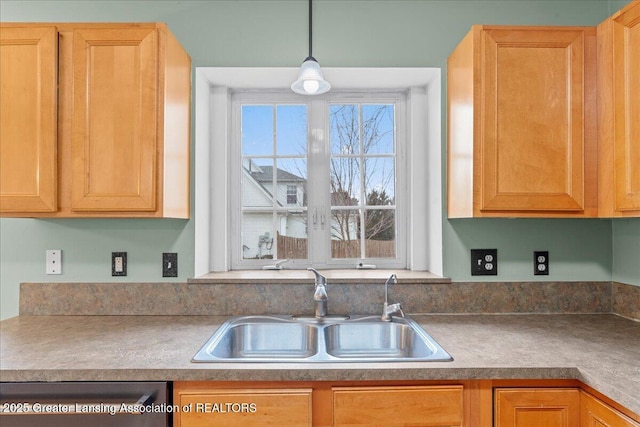 kitchen featuring dishwashing machine, pendant lighting, and a sink