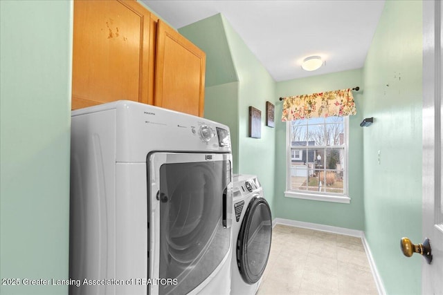 washroom with cabinet space, baseboards, and independent washer and dryer