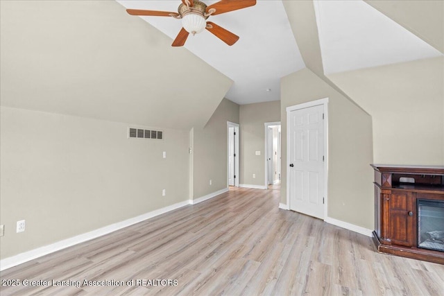 bonus room featuring light wood-style flooring, visible vents, baseboards, and a glass covered fireplace