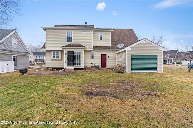 rear view of property featuring a garage and a lawn