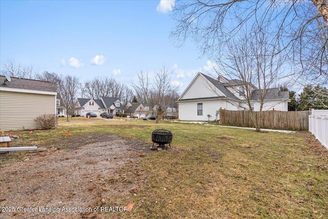 view of yard featuring a fire pit, fence, and a residential view