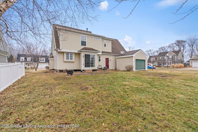 rear view of property featuring a yard, fence, and a garage