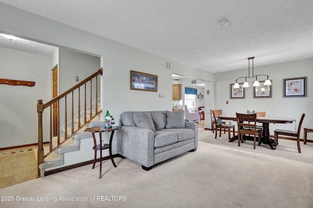 living room with a textured ceiling, stairway, baseboards, and light colored carpet