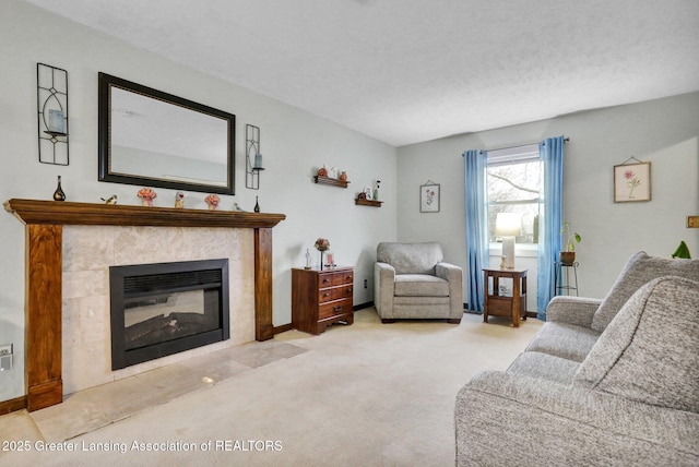 carpeted living area with baseboards, a textured ceiling, and a tile fireplace