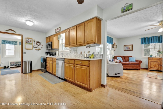 kitchen with ceiling fan, appliances with stainless steel finishes, light countertops, and light wood-style flooring