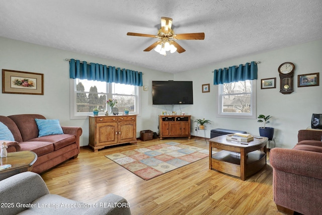 living area featuring light wood-style flooring, ceiling fan, and a textured ceiling