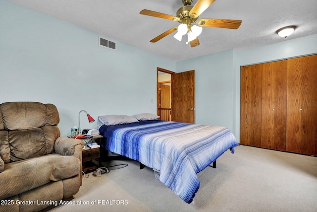 carpeted bedroom featuring ceiling fan, a textured ceiling, a closet, and visible vents