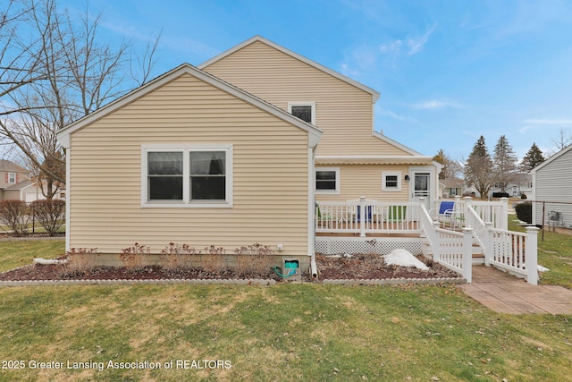 rear view of house featuring a deck and a lawn