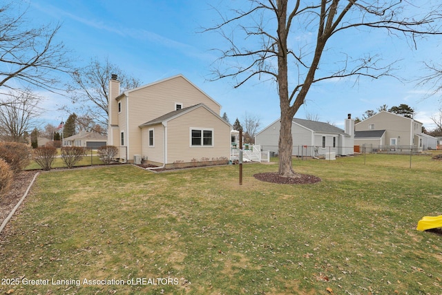 rear view of property featuring a yard, a chimney, and fence