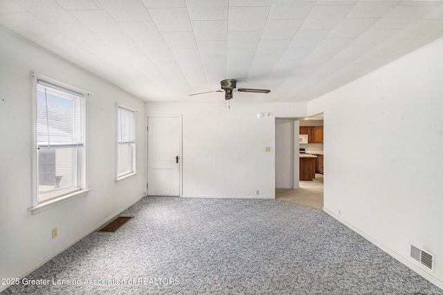 spare room featuring a ceiling fan, visible vents, and baseboards