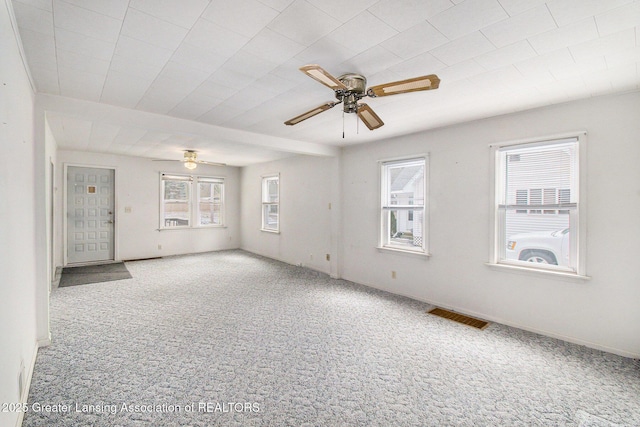 carpeted empty room featuring a ceiling fan, visible vents, and baseboards