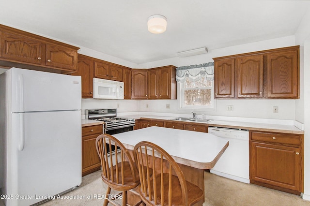 kitchen featuring brown cabinets, light countertops, a kitchen island, a sink, and white appliances