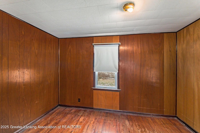 empty room with hardwood / wood-style floors and wooden walls