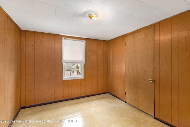 unfurnished room featuring wood walls and baseboards