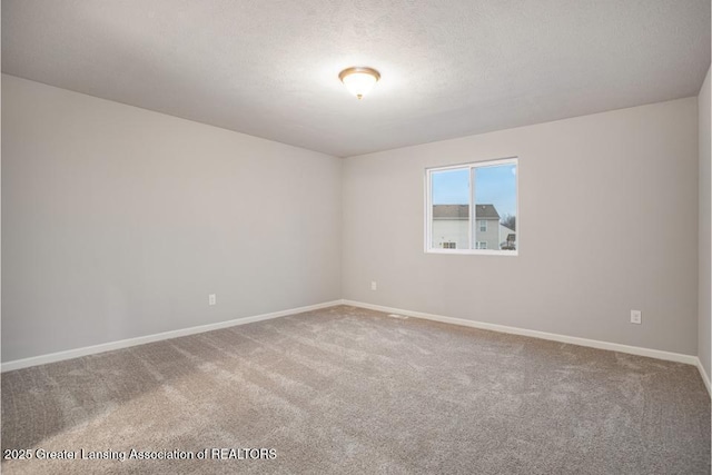 empty room featuring carpet floors, a textured ceiling, and baseboards