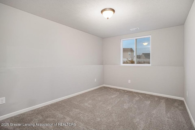 empty room featuring a textured ceiling, carpet floors, visible vents, and baseboards