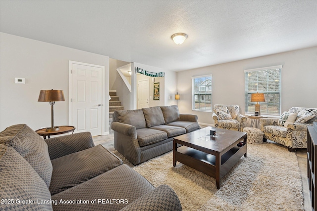 living area featuring light wood-style flooring, stairway, and a textured ceiling