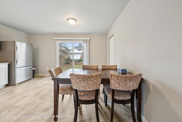 dining area with light wood-style flooring and baseboards