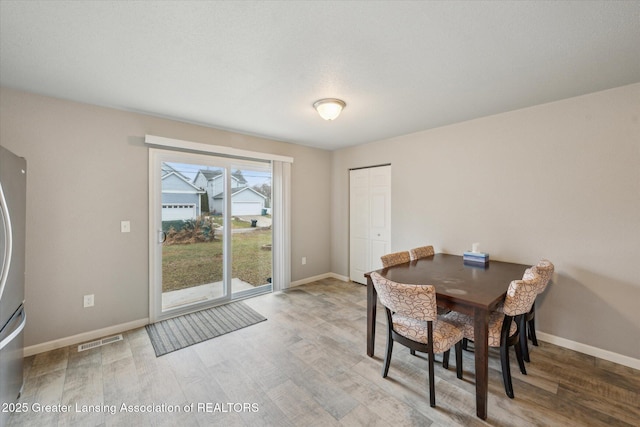 dining space featuring visible vents, baseboards, and wood finished floors