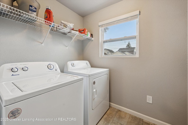 clothes washing area with laundry area, baseboards, light wood-style flooring, and washing machine and clothes dryer