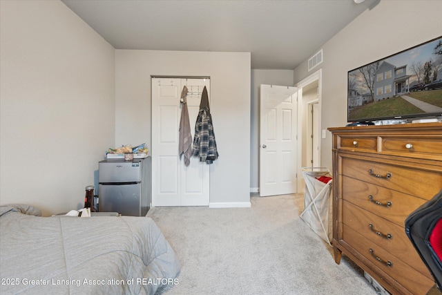 bedroom with baseboards, freestanding refrigerator, visible vents, and light colored carpet