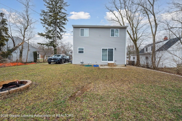 back of house featuring entry steps, a lawn, and a fire pit