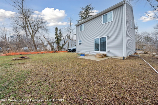 rear view of house featuring entry steps, an outdoor fire pit, and a lawn