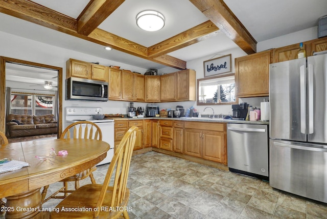 kitchen featuring a sink, a ceiling fan, light countertops, appliances with stainless steel finishes, and beamed ceiling