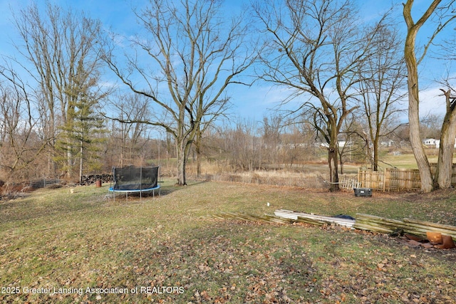 view of yard featuring a trampoline and fence