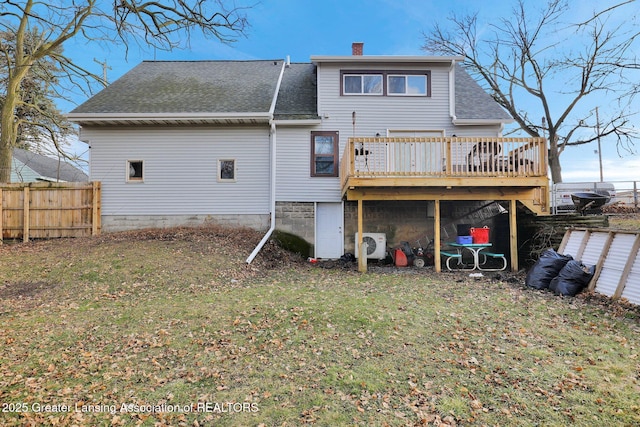 back of house featuring a shingled roof, a lawn, a chimney, fence, and a wooden deck