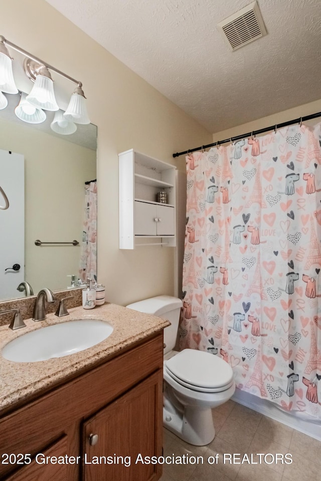 bathroom with visible vents, toilet, vanity, a textured ceiling, and tile patterned floors