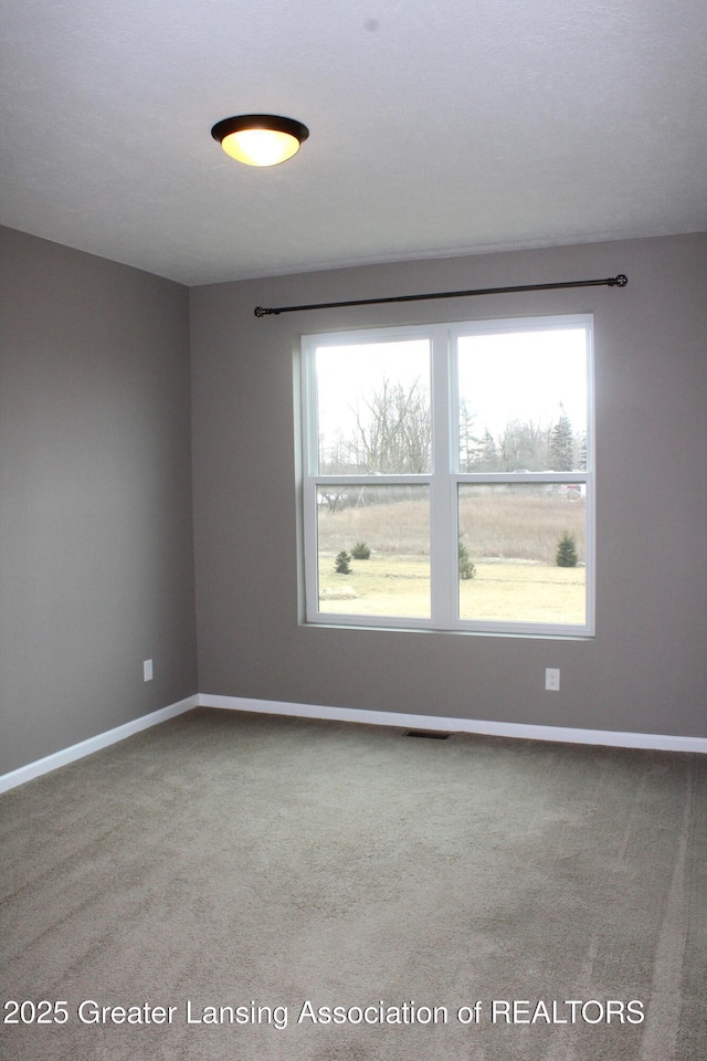 carpeted empty room featuring visible vents and baseboards