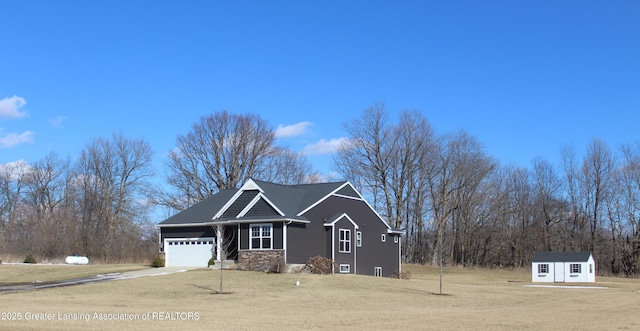 view of front of property featuring an attached garage, a front yard, a shed, stone siding, and driveway